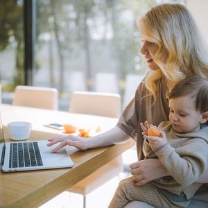 woman-holding-baby-and-on-computer