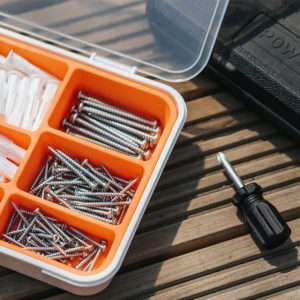 Tool box with screws and a short handle phillips head screwdriver.